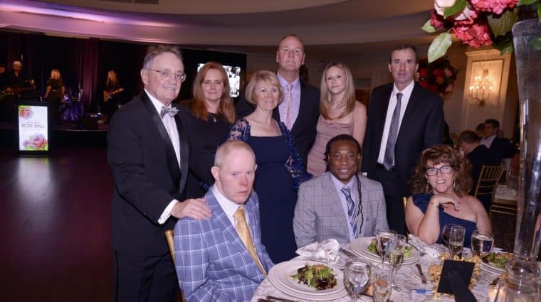 A group of Rose Ball attendees pose for a photo at dinner
